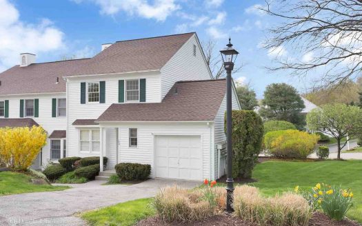 White home with green grass and budding plants in New York